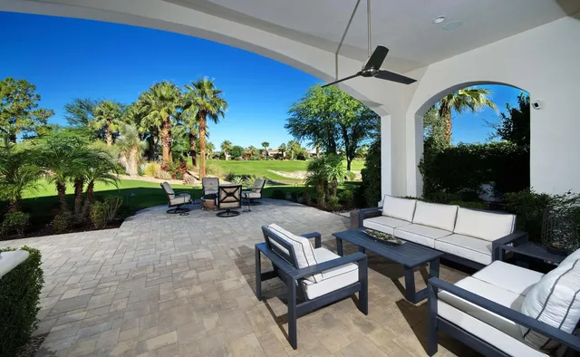 a view of a patio with couches table and chairs potted plants and palm tree