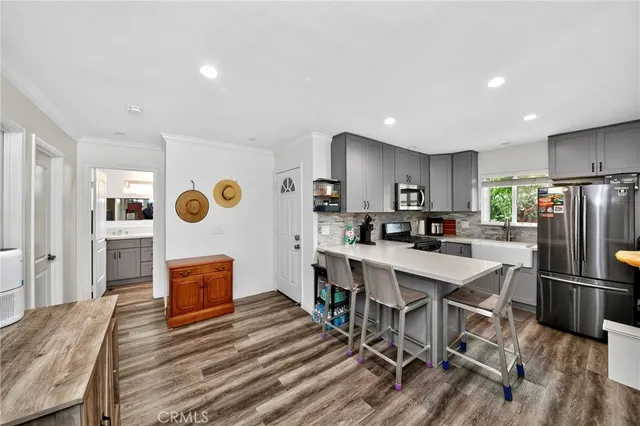 a kitchen with stainless steel appliances a stove a refrigerator sink cabinets and couches with wooden floor