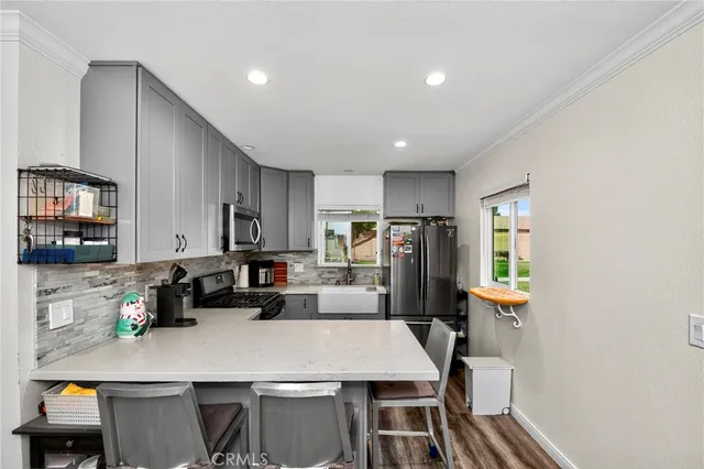 a kitchen with stainless steel appliances a dining table chairs refrigerator and sink
