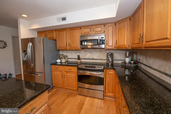 a kitchen with stainless steel appliances granite countertop a refrigerator stove top oven and sink
