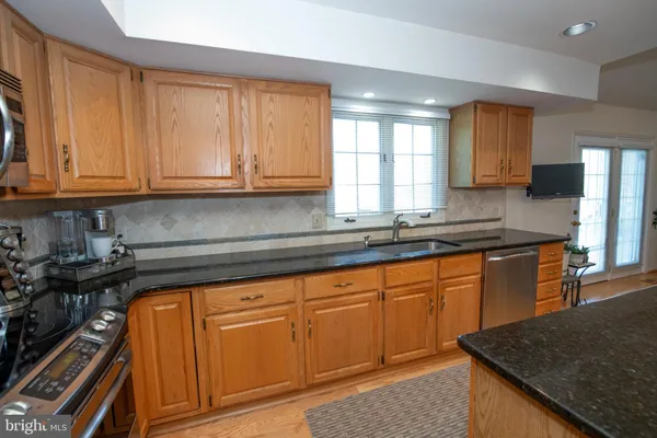 a kitchen with granite countertop wooden cabinets and a stove top oven