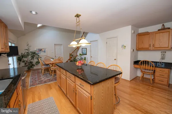a kitchen with stainless steel appliances granite countertop a kitchen island a stove a sink a dining table and chairs with wooden floor