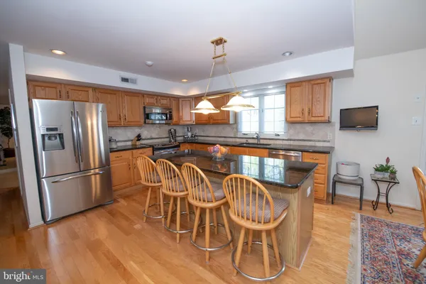 a kitchen with stainless steel appliances granite countertop a dining table chairs refrigerator and sink