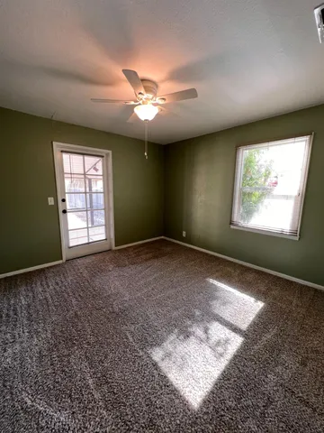 an empty room with a chandelier fan and windows