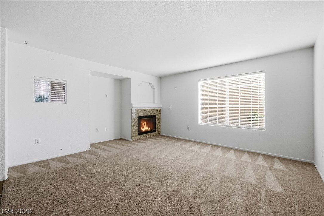 1851 Hillpointe Road, Unit 1311 Henderson, NV 89074 - Photo 10 of 47 Unfurnished living room with a tiled fireplace and light carpet