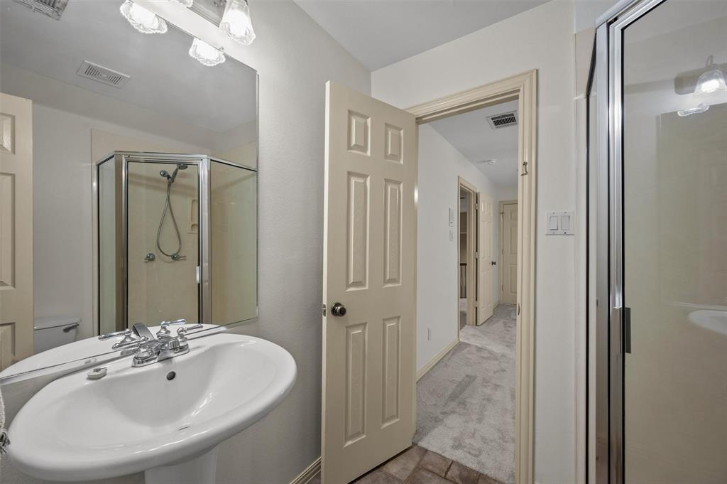 5607 Ranger Drive Rockwall, TX 75032 - Photo 30 of 40 Bathroom featuring a pedestal sink with chrome fixtures, a mirrored wall, and a corner shower enclosure with a glass door