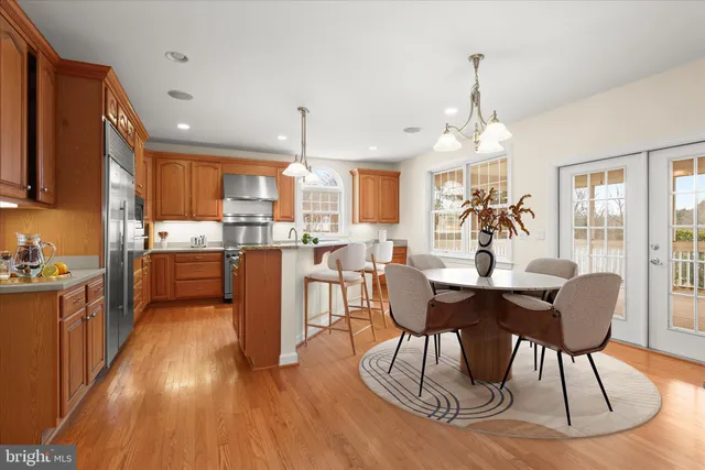 a living room with stainless steel appliances wooden floor and a kitchen view
