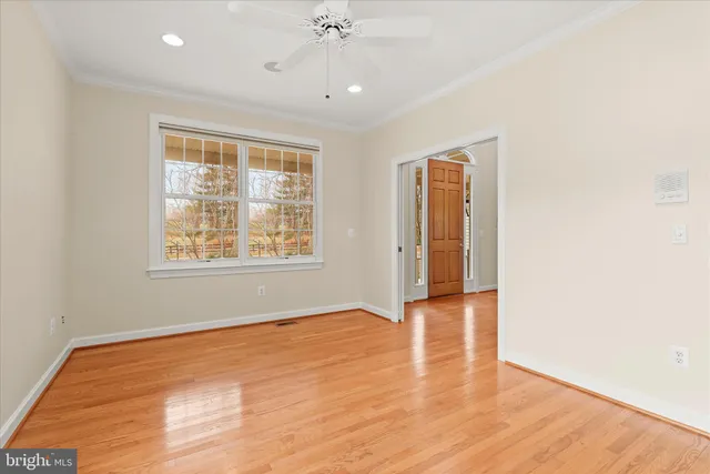 a view of an empty room with wooden floor and windows
