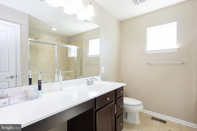 a bathroom with a sink a toilet a mirror and a window