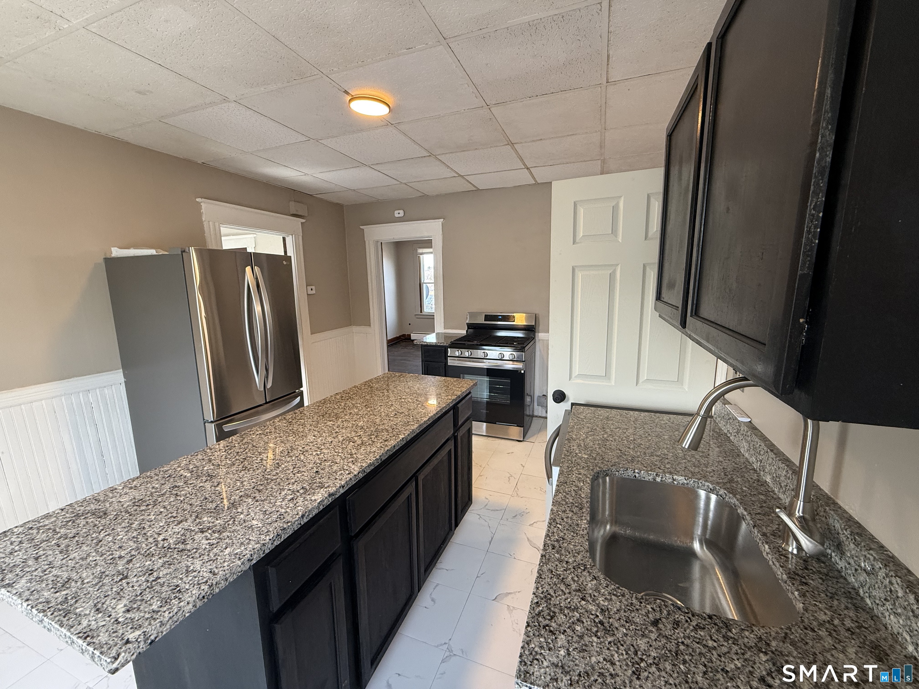 a kitchen with granite countertop stainless steel appliances a sink stove refrigerator a sink and dishwasher