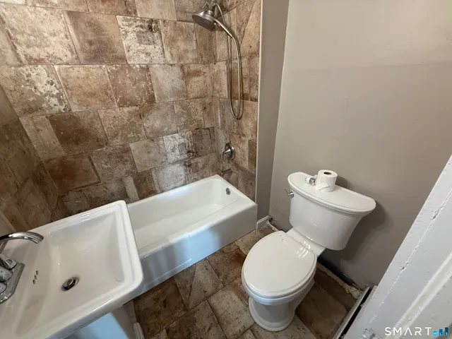 a white toilet sitting next to a bath tub