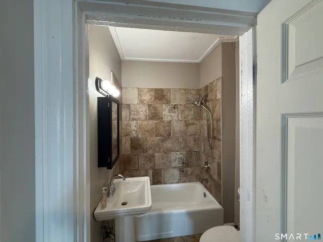 a bathroom with a sink and mirror with bathtub