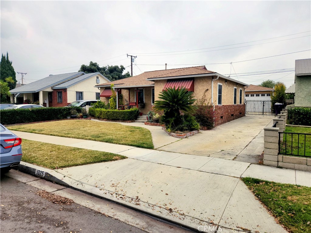 1325 West 34th Street Long Beach, CA 90810 - Photo 35 of 35 a view of a white house with a yard and table and chairs under an umbrella