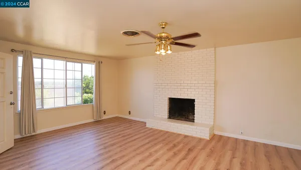 a kitchen with a refrigerator a stove top oven a large window with wooden floor and cabinets