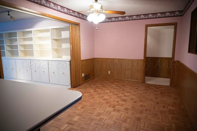 an empty room with windows and chandelier fan