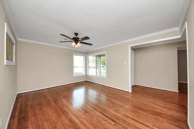 a view of empty room with wooden floor and fan