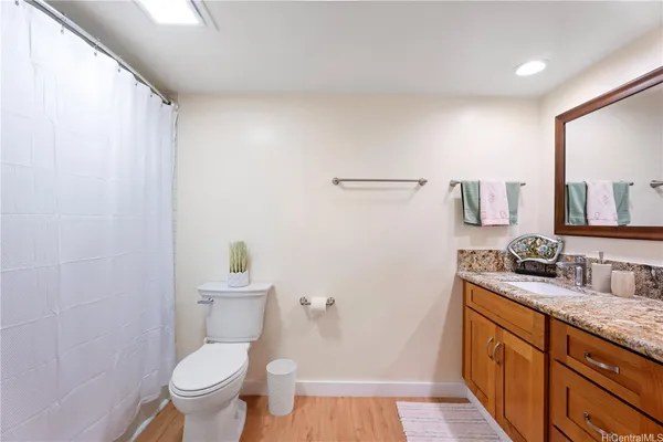a bathroom with a granite countertop toilet sink and mirror