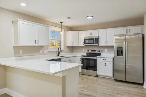 a kitchen with a sink a stove a refrigerator a microwave and cabinets