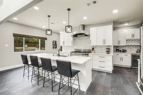 a kitchen with stainless steel appliances kitchen island granite countertop a wooden table chairs and white cabinets