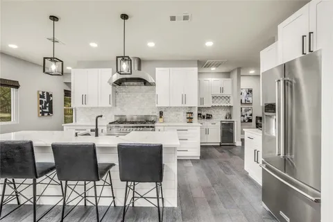 a kitchen with stainless steel appliances granite countertop a sink a stove a refrigerator and island with wooden floor