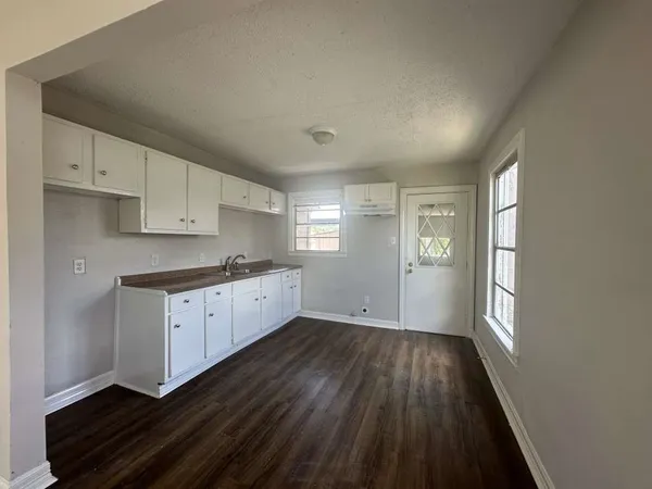a kitchen with wooden floors and white cabinets