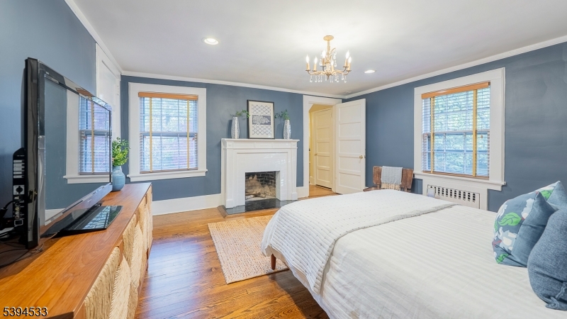 16 W Road Short Hills, NJ 07078 - Photo 28 of 47 a spacious bedroom with a balcony a bed and a chandelier