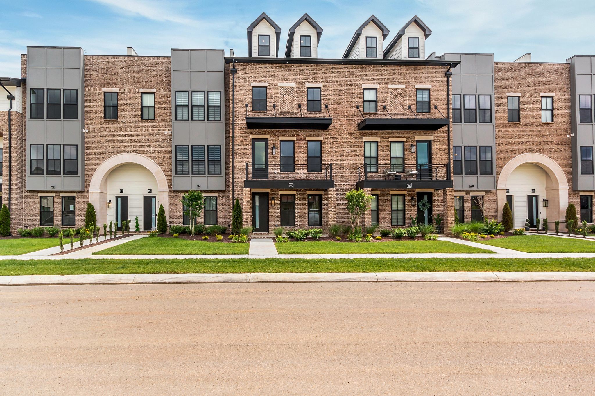 a view of a brick house with a big yard and a large parking space