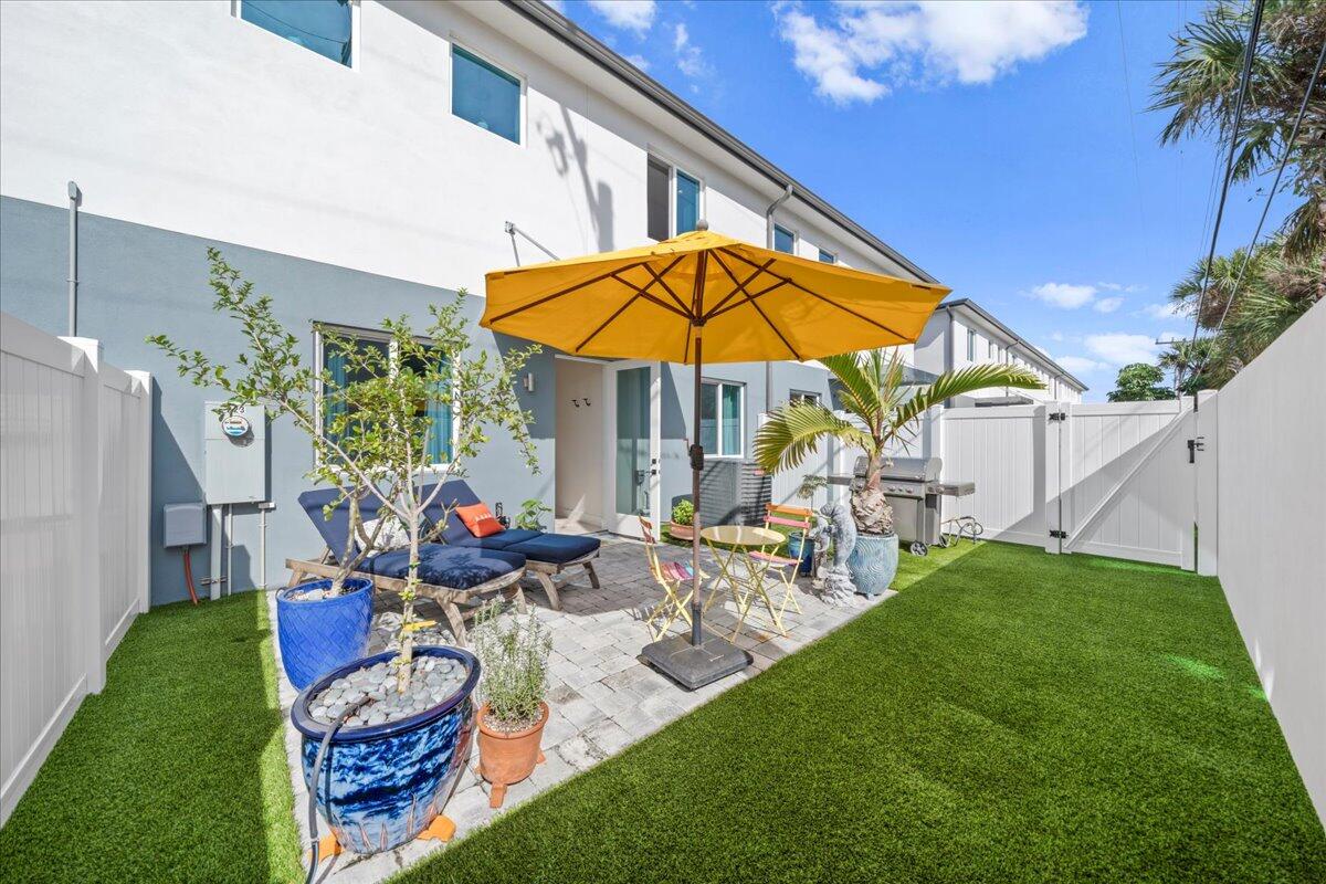 223 6th Avenue Indialantic, FL 32903 - Photo 14 of 26 a view of a backyard with table and chairs under an umbrella with a fire pit and potted plants