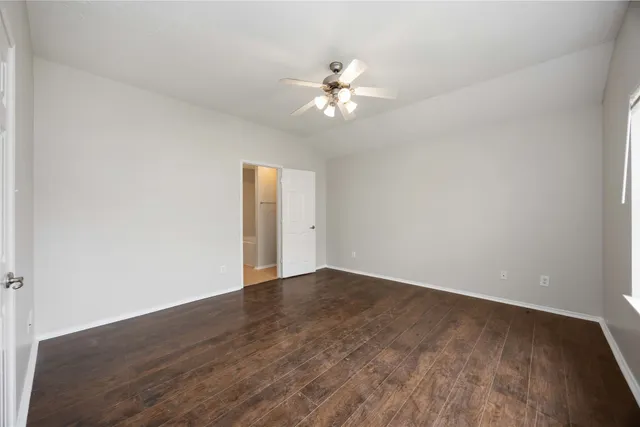 an empty room with wooden floor fan and window