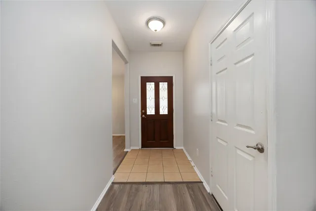 a view of a hallway with wooden floor and a bathroom