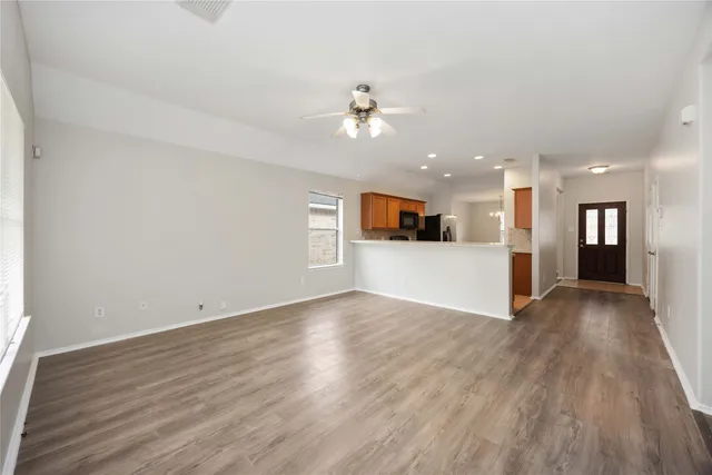 an empty space with kitchen view and wooden floor