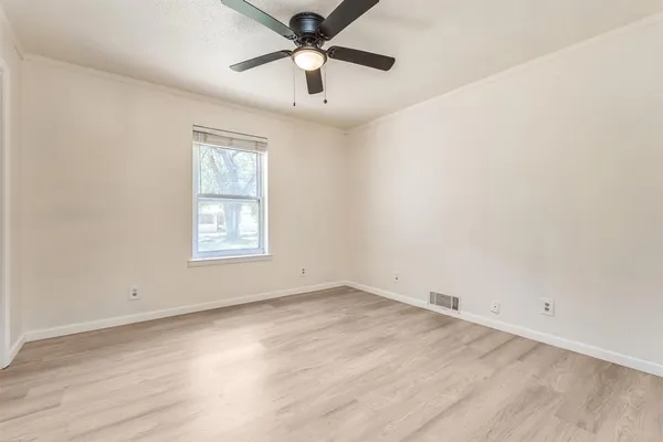 an empty room with a window and a fan