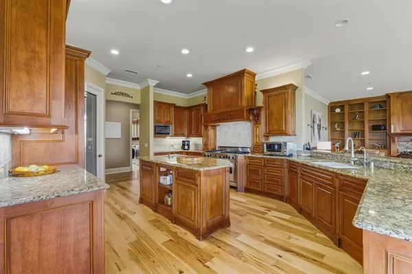 a large kitchen with stainless steel appliances granite countertop a stove refrigerator and a sink
