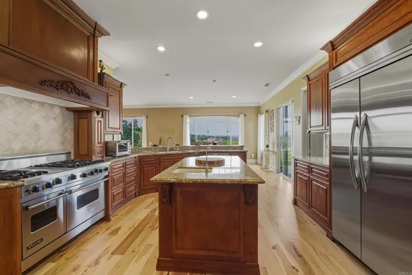 a kitchen with stainless steel appliances granite countertop a stove a sink and a refrigerator