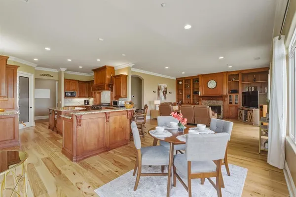 a dining room with stainless steel appliances kitchen island granite countertop a dining table chairs and a living room view