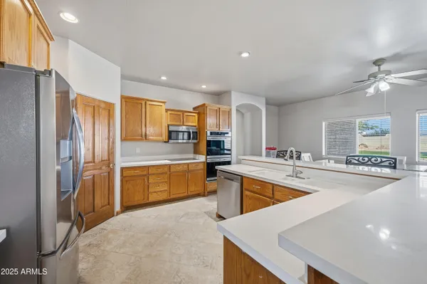 a kitchen with stainless steel appliances granite countertop a refrigerator a sink dishwasher a stove and white countertops with wooden floor
