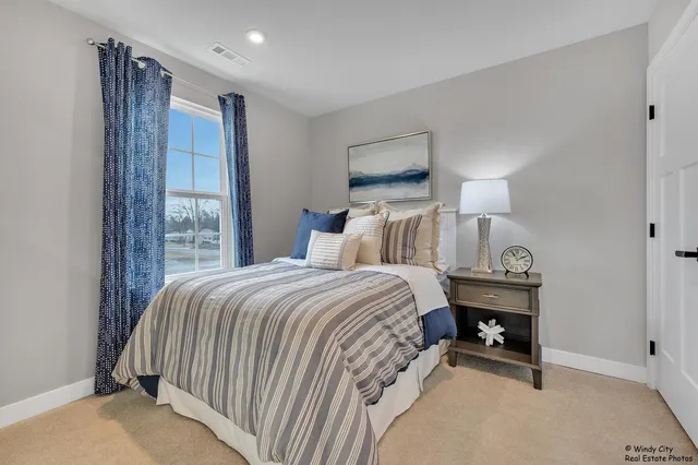 a bedroom with a bed a lamp and a large window