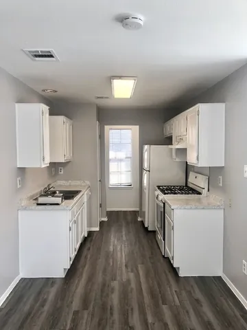 a kitchen with a stove wooden floor and cabinets