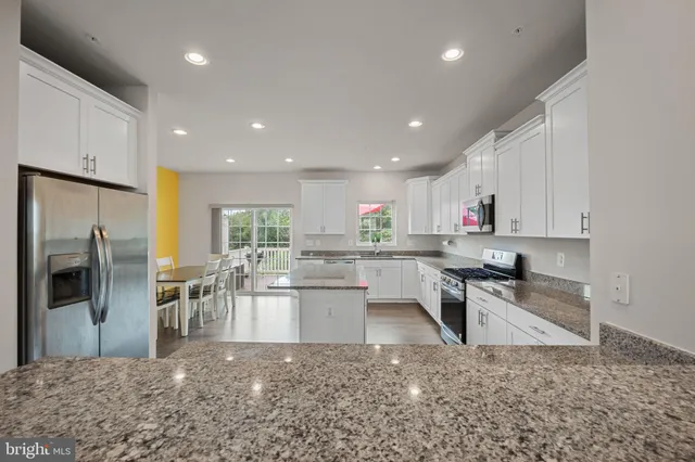 a kitchen with stainless steel appliances granite countertop a sink refrigerator and cabinets