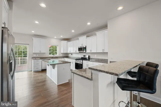 a kitchen with a sink dishwasher stove top oven and cabinets with wooden floor