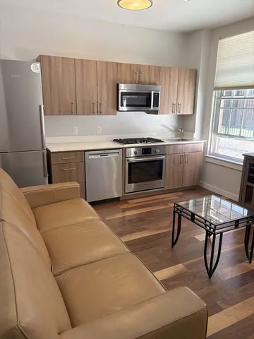 a living room with stainless steel appliances kitchen island granite countertop furniture and a fireplace