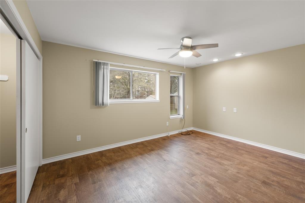 1621 Baseball Loop Diana, TX 75640 - Photo 13 of 38 an empty room with wooden floor ceiling fan and windows