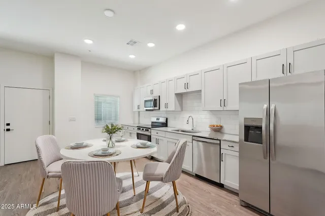 a kitchen with stainless steel appliances a table and chairs