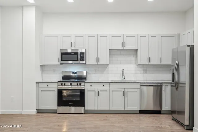 a kitchen with granite countertop white cabinets and stainless steel appliances