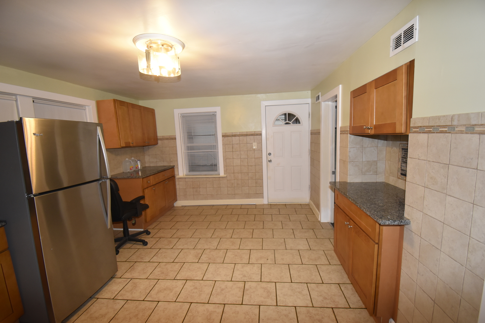 2448 South Homan Avenue, Unit 1 Chicago, IL 60623 - Photo 6 of 12 a view of a refrigerator in kitchen and an empty room in wooden floor