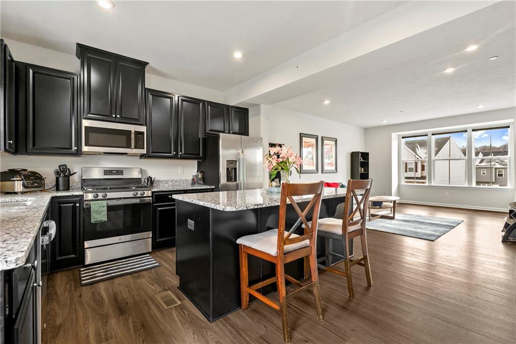 327 Helenium Drive Mars, PA 16046 - Photo 7 of 35 a kitchen with granite countertop a stove top oven a sink dishwasher a dining table and chairs with wooden floor