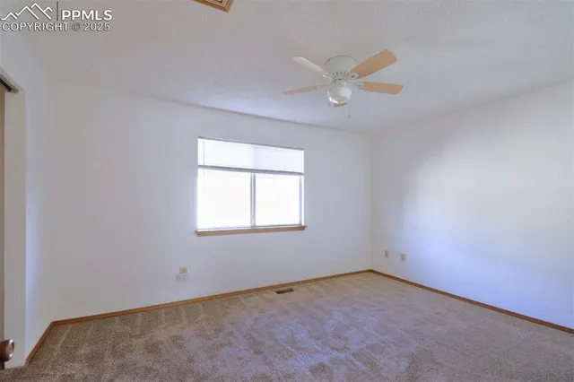 an empty room with a window and a fan