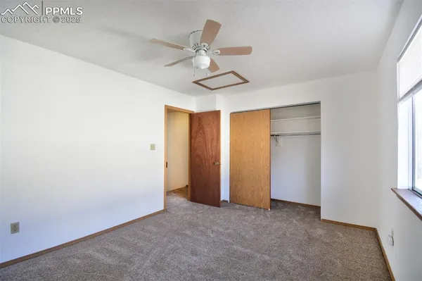 an empty room with windows and fan