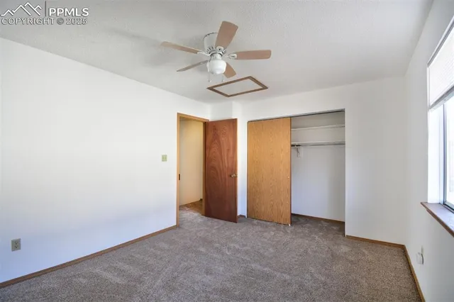 an empty room with windows and fan