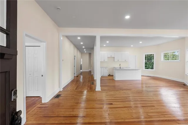a view of an empty room with wooden floor and a kitchen